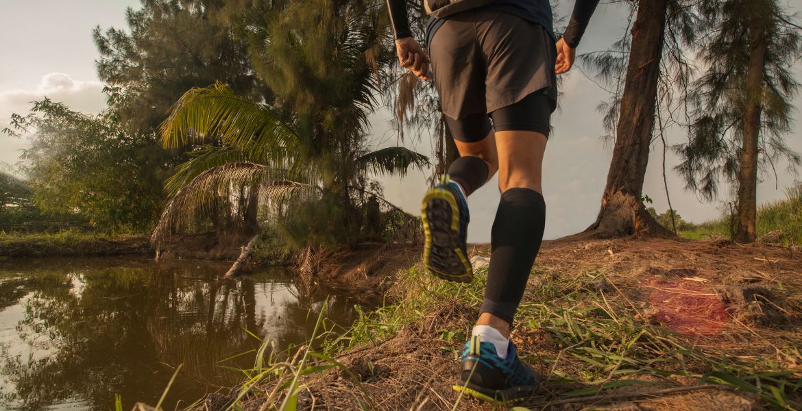 An amateur athlete running on a scenic trail with mountains in the background, building endurance for their next race