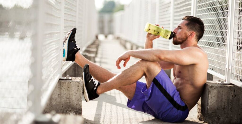 Resting athlete drinking water during running training