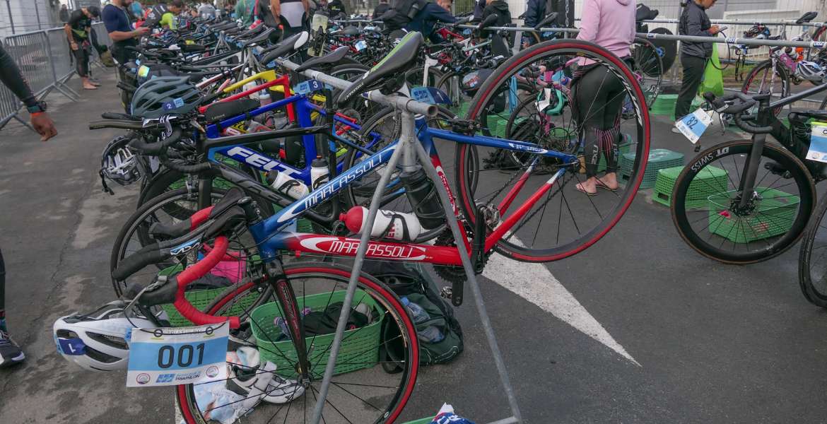 Bicycles racked in a well-organized triathlon transition zone, showcasing efficient setup for faster T1 and T2 transitions